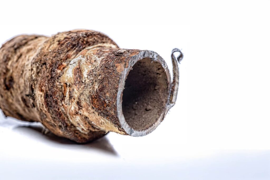 Detailed macro shot of a section of degraded, rusted piping showing external corrosion and mineral deposits.